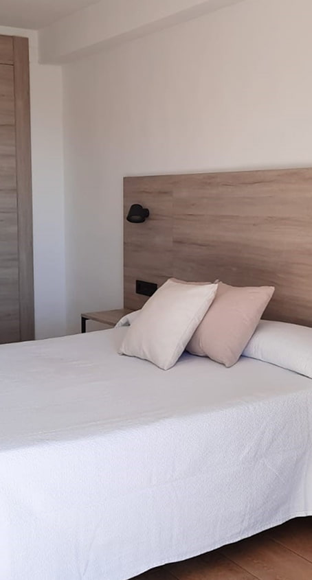 Habitación con cama doble, en tonos blancos y arena