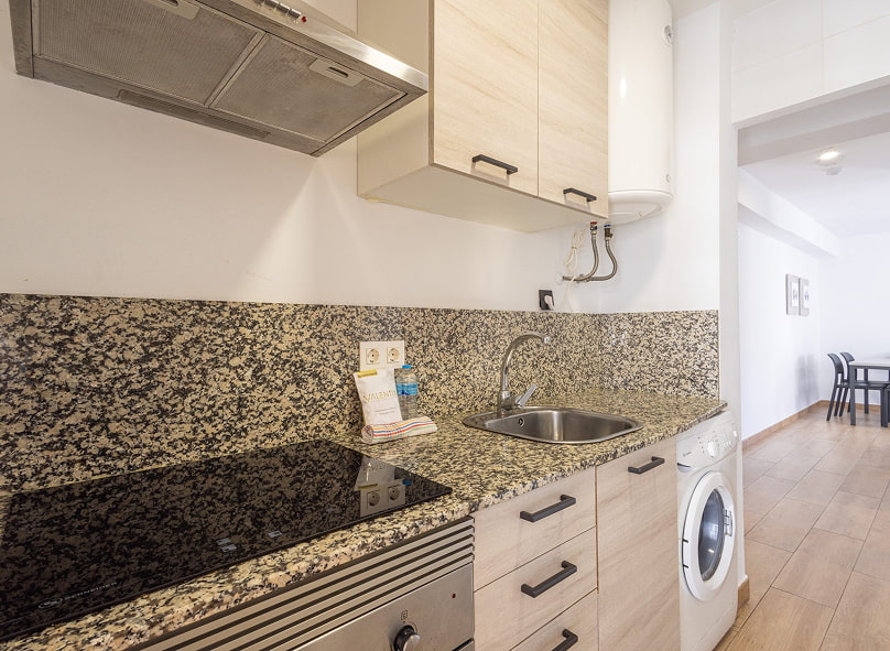 Detalle de la zona de cocina, con vitrocerámica, horno  lavadora