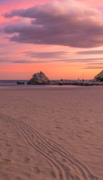 Imagen de un atardecer en la playa, con el cielo de color rojizo