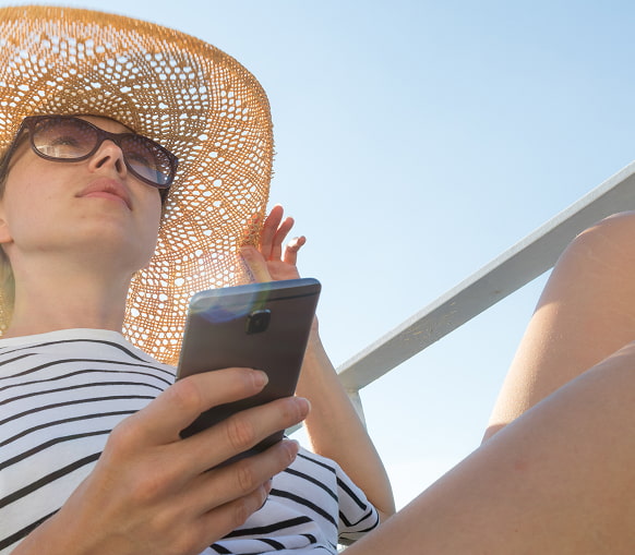 Mejor precio garantizado Mujer joven consultando la web de Apartamentos Odysea desde el móvil