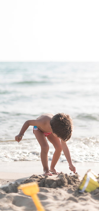 Perfectos para familias Niño jugando con la arena en la orilla del mar